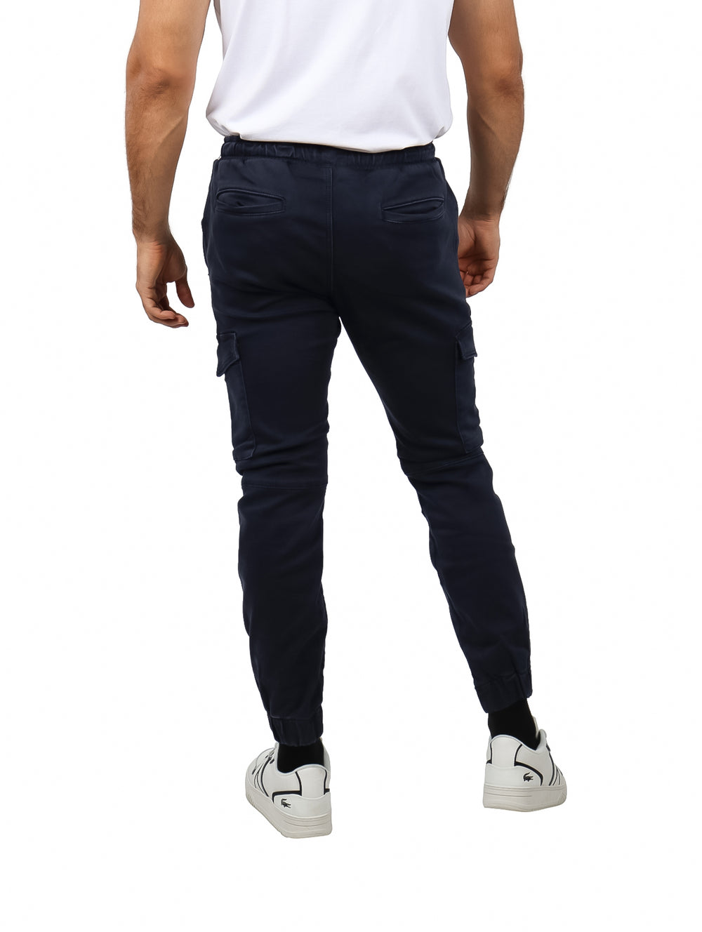 Hombre vistiendo pantalones jogger color azul marino con bolsillos laterales y calzado blanco.