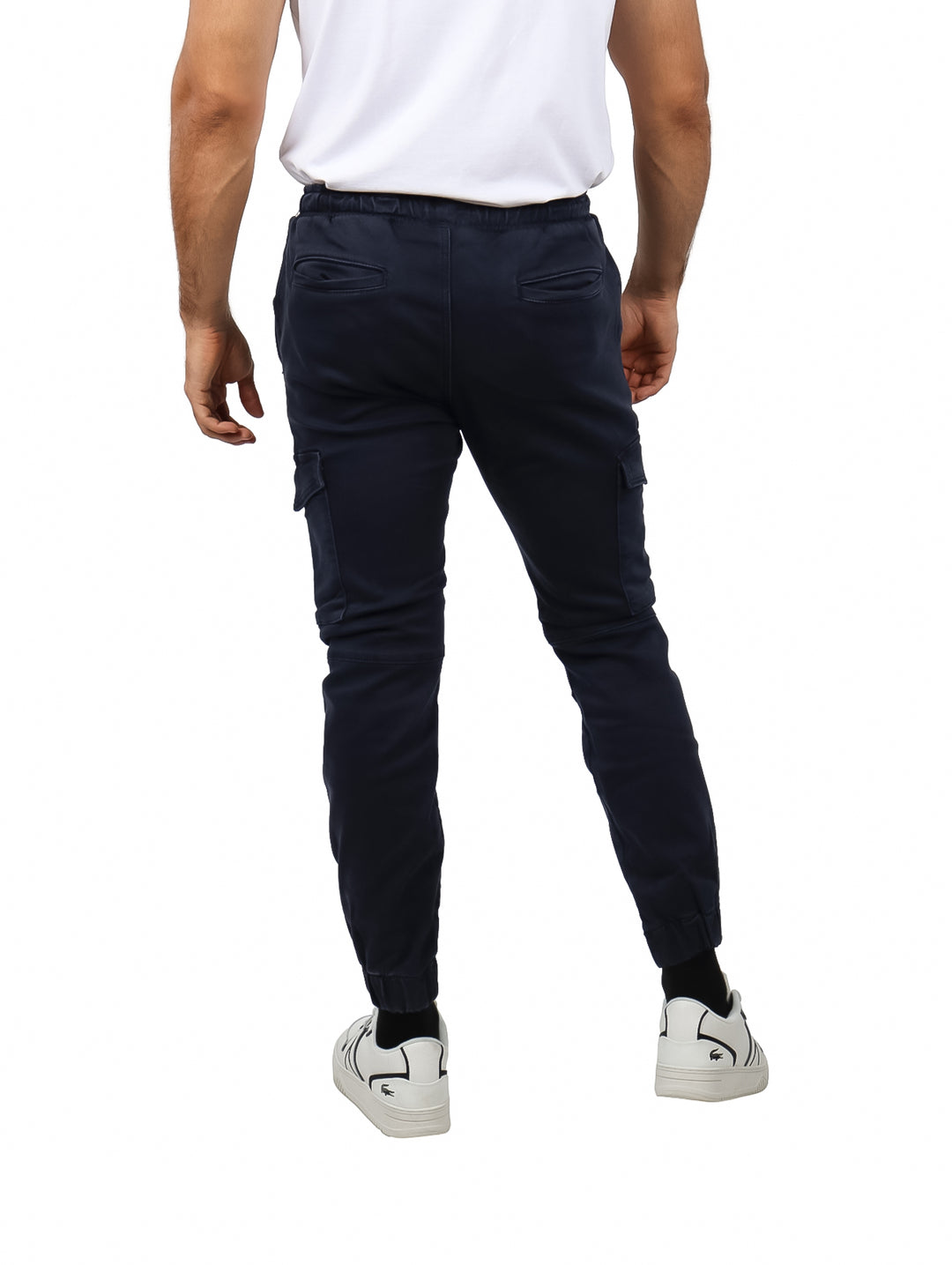 Hombre vistiendo pantalones jogger color azul marino con bolsillos laterales y calzado blanco.