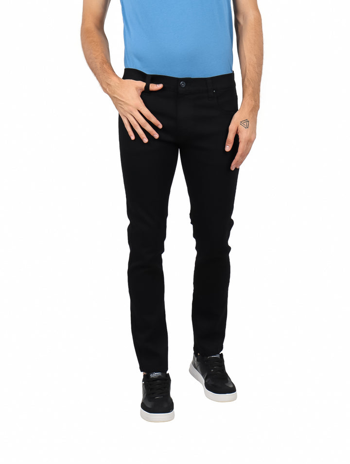 Hombre vistiendo jeans negros de corte ajustado y camiseta azul.