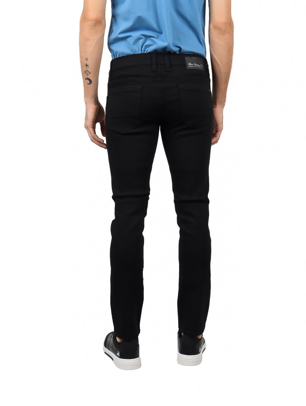 Hombre vistiendo jeans negros de corte ajustado y camiseta azul.