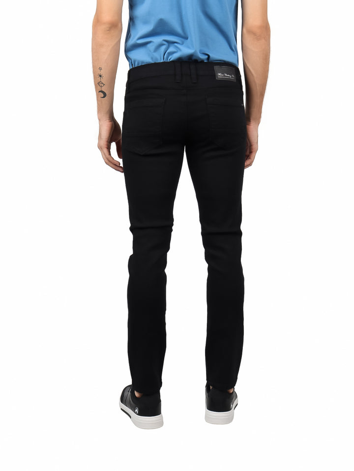 Hombre vistiendo jeans negros de corte ajustado y camiseta azul.