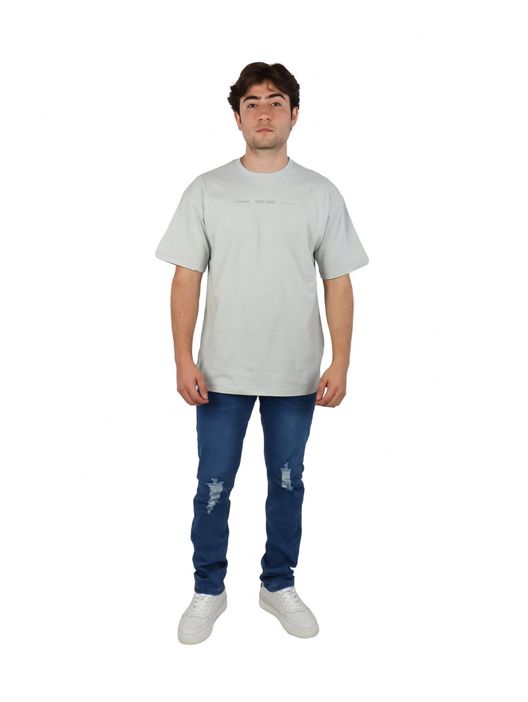 Hombre vistiendo playera oversize color gris de manga corta y cuello redondo con texto pequeño en el pecho.