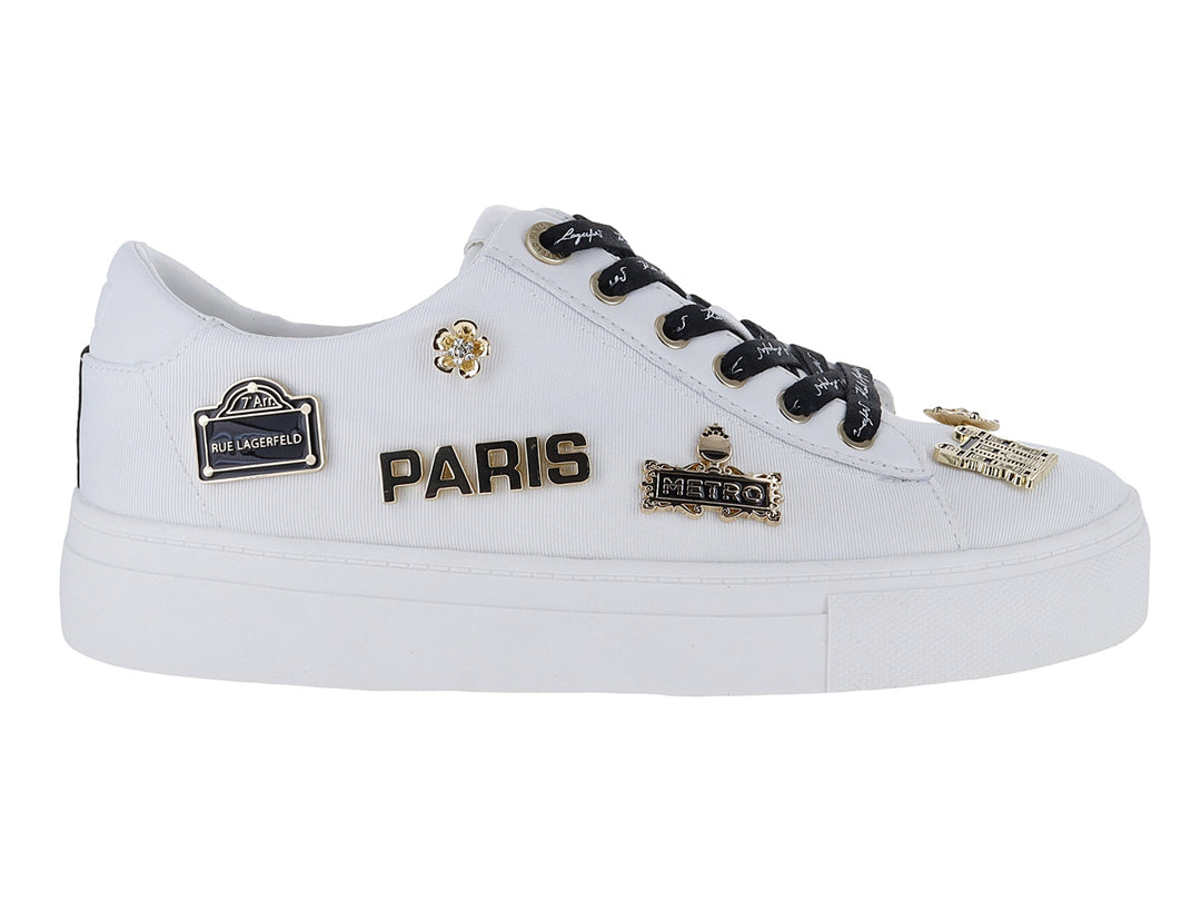 Tenis blancos Karl Lagerfeld con agujetas negras y pines decorativos dorados con la palabra Paris.