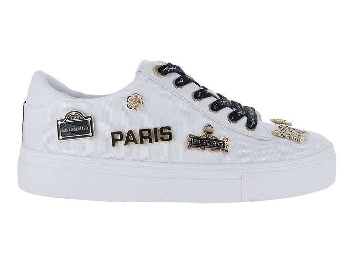 Tenis blancos Karl Lagerfeld con agujetas negras y pines decorativos dorados con la palabra Paris.