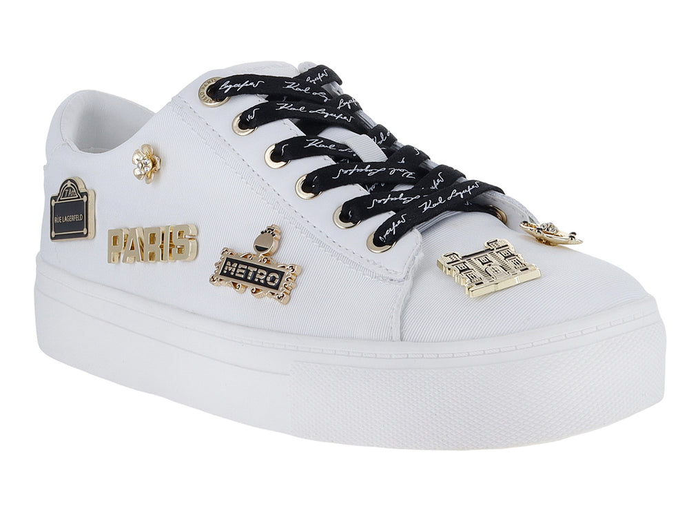 Tenis blancos Karl Lagerfeld con agujetas negras y pines decorativos dorados con la palabra Paris.