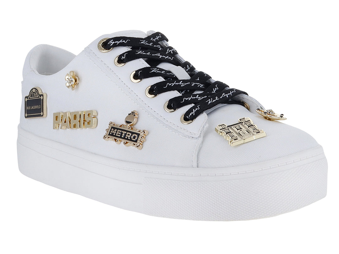 Tenis blancos Karl Lagerfeld con agujetas negras y pines decorativos dorados con la palabra Paris.