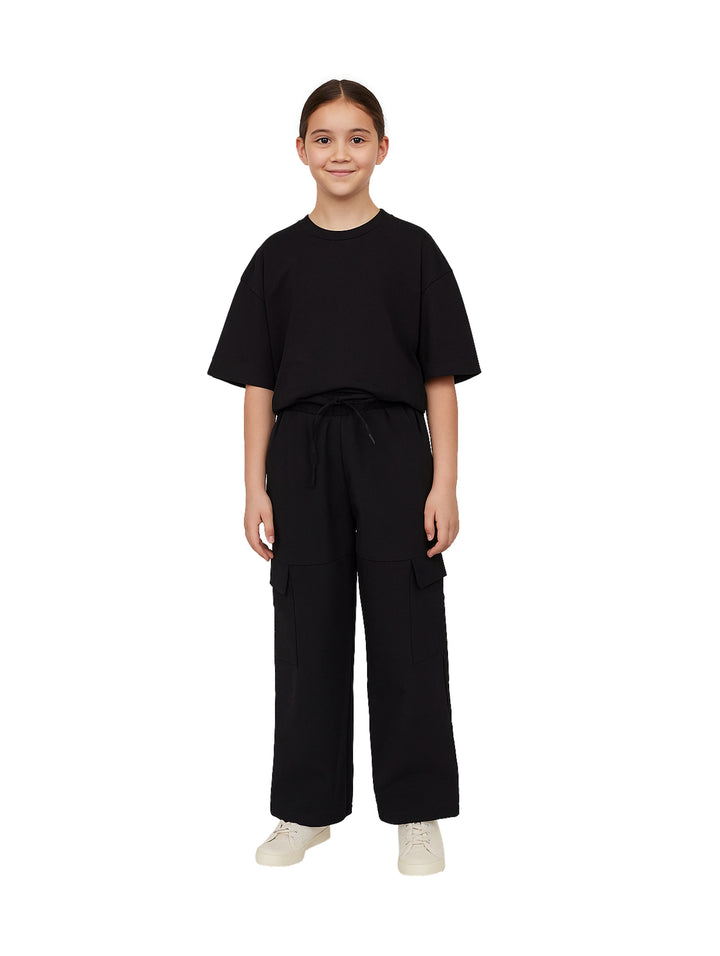 Niña modelando un pantalón cargo negro de pierna ancha con cintura ajustable.