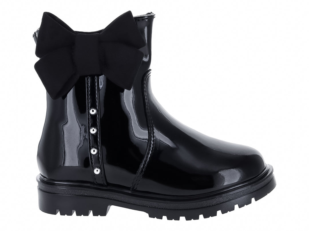 Bota de charol negro con moño decorativo y detalles metálicos.