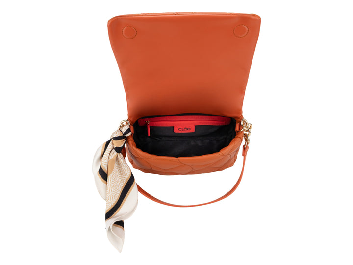 Bolso de hombro Cloe color tan con diseño acolchado, detalles en cadena dorada y un pañuelo decorativo lateral.