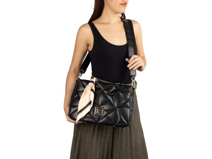 Bolso de hombro Cloe color negro con diseño acolchado, asa de cadena dorada y un pañuelo beige decorativo.