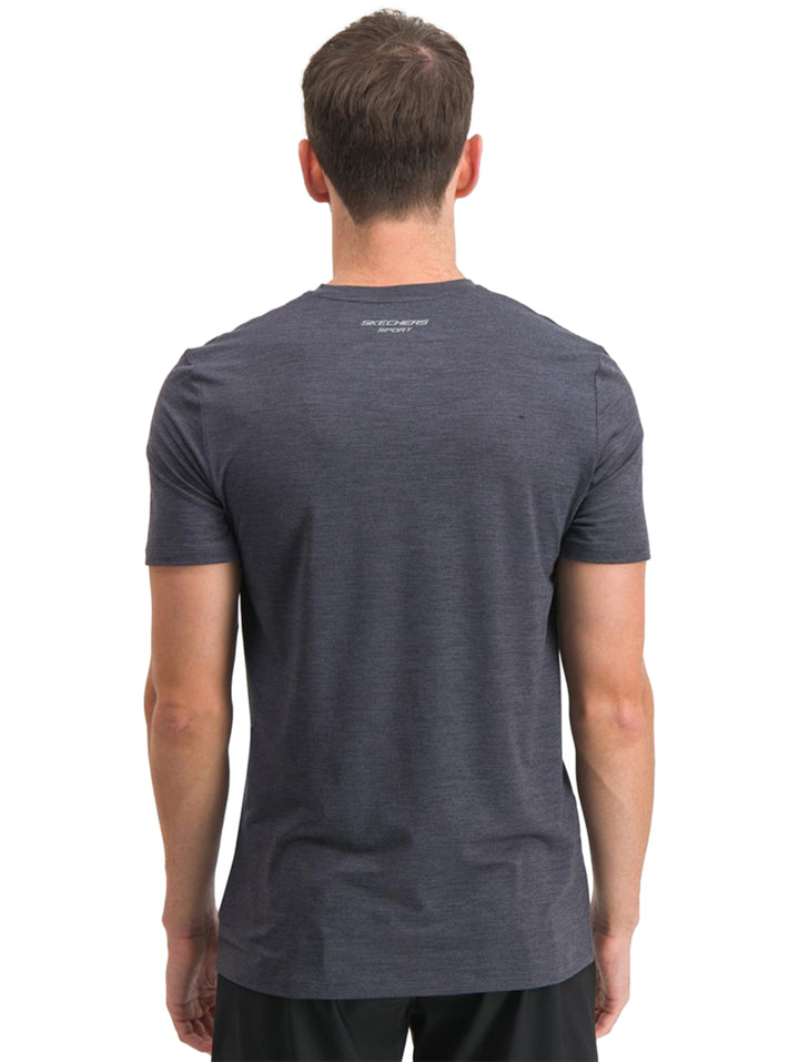 Hombre vistiendo una playera deportiva de manga corta color negro marca Skechers con cuello redondo.