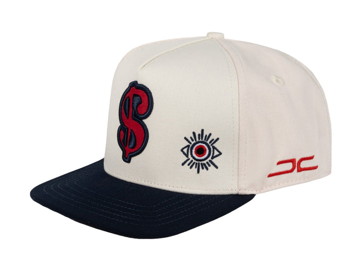 Gorra snapback color beige con visera azul marino y bordados en rojo y azul.