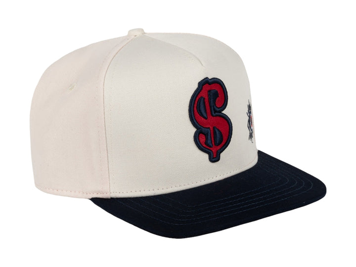 Gorra snapback color beige con visera azul marino y bordados en rojo y azul.