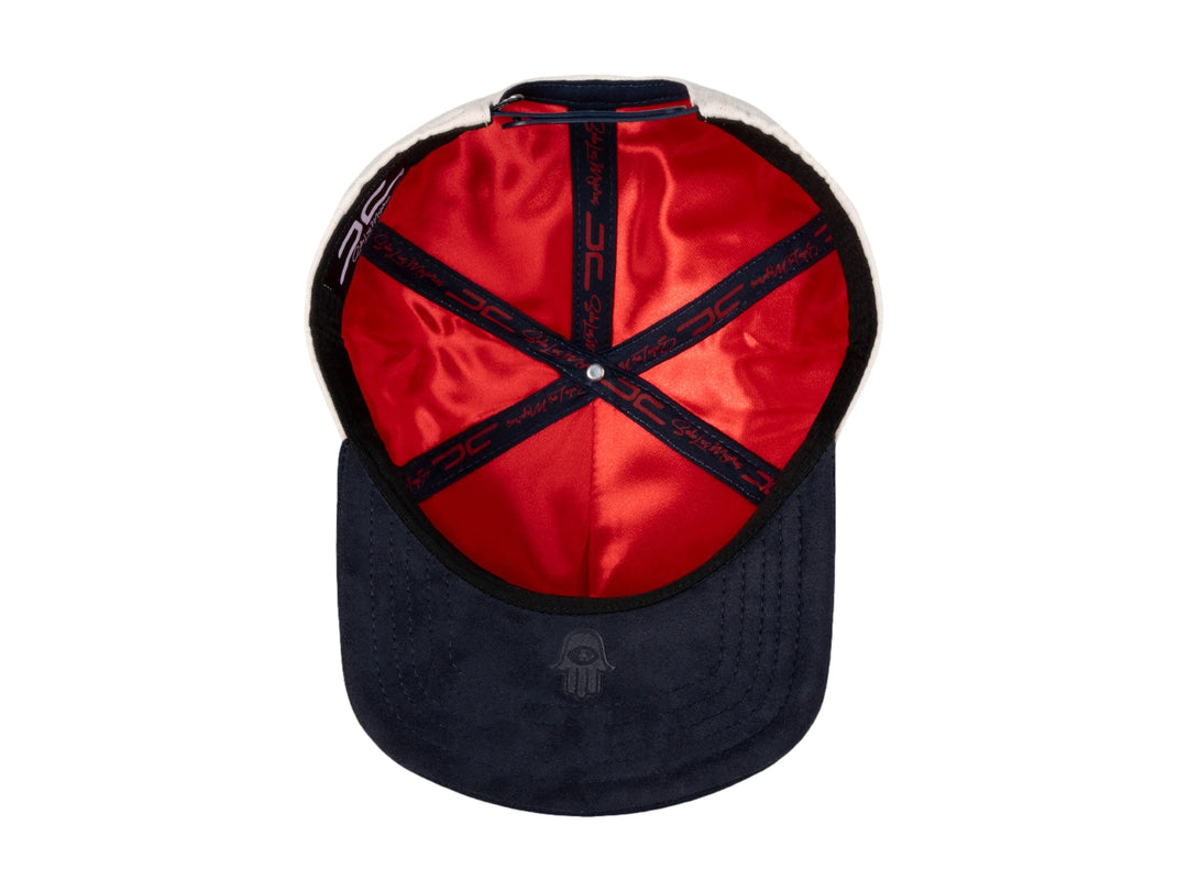 Gorra snapback color beige con visera azul marino y bordados en rojo y azul.