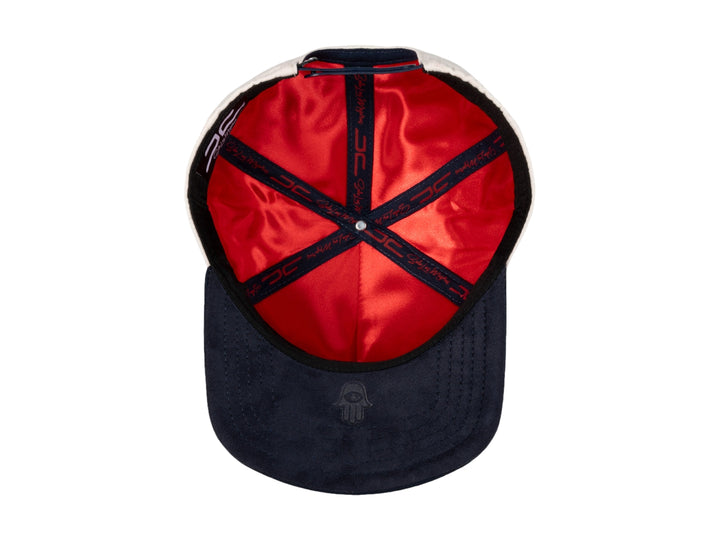 Gorra snapback color beige con visera azul marino y bordados en rojo y azul.