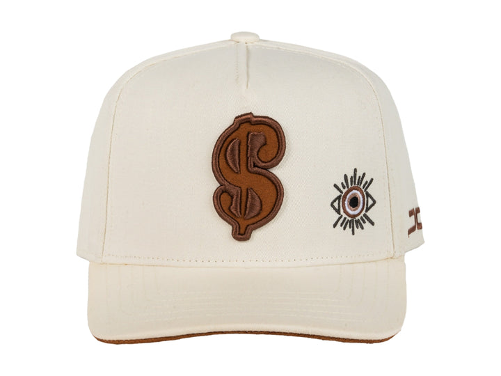 Gorra snapback color beige con bordados en marrón, incluyendo un símbolo de dólar y un ojo.