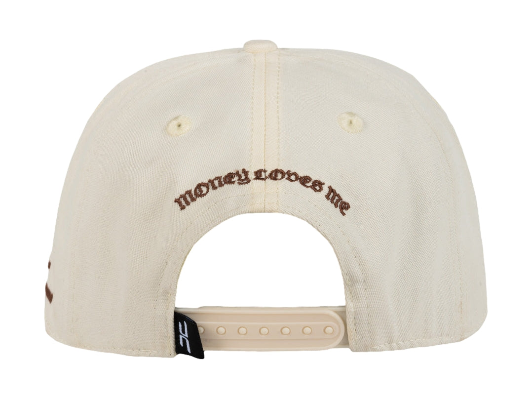 Gorra snapback color beige con bordados en marrón, incluyendo un símbolo de dólar y un ojo.