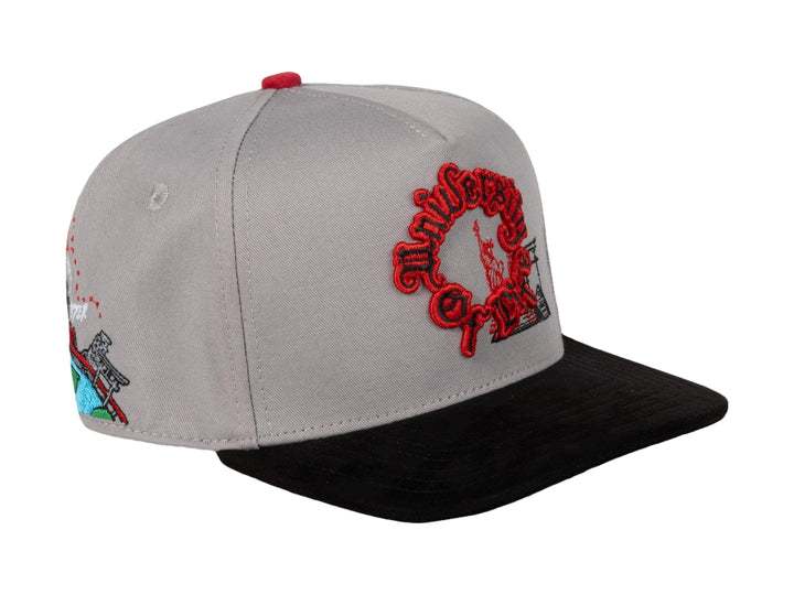Gorra snapback de color gris con visera negra y bordados en color rojo en el frente y lateral.