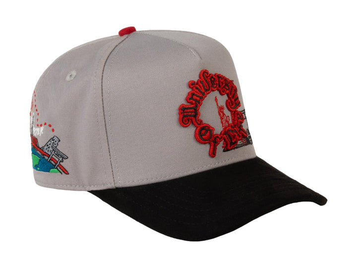 Gorra JC HATS color gris con visera negra y bordado rojo frontal que dice University of Life.