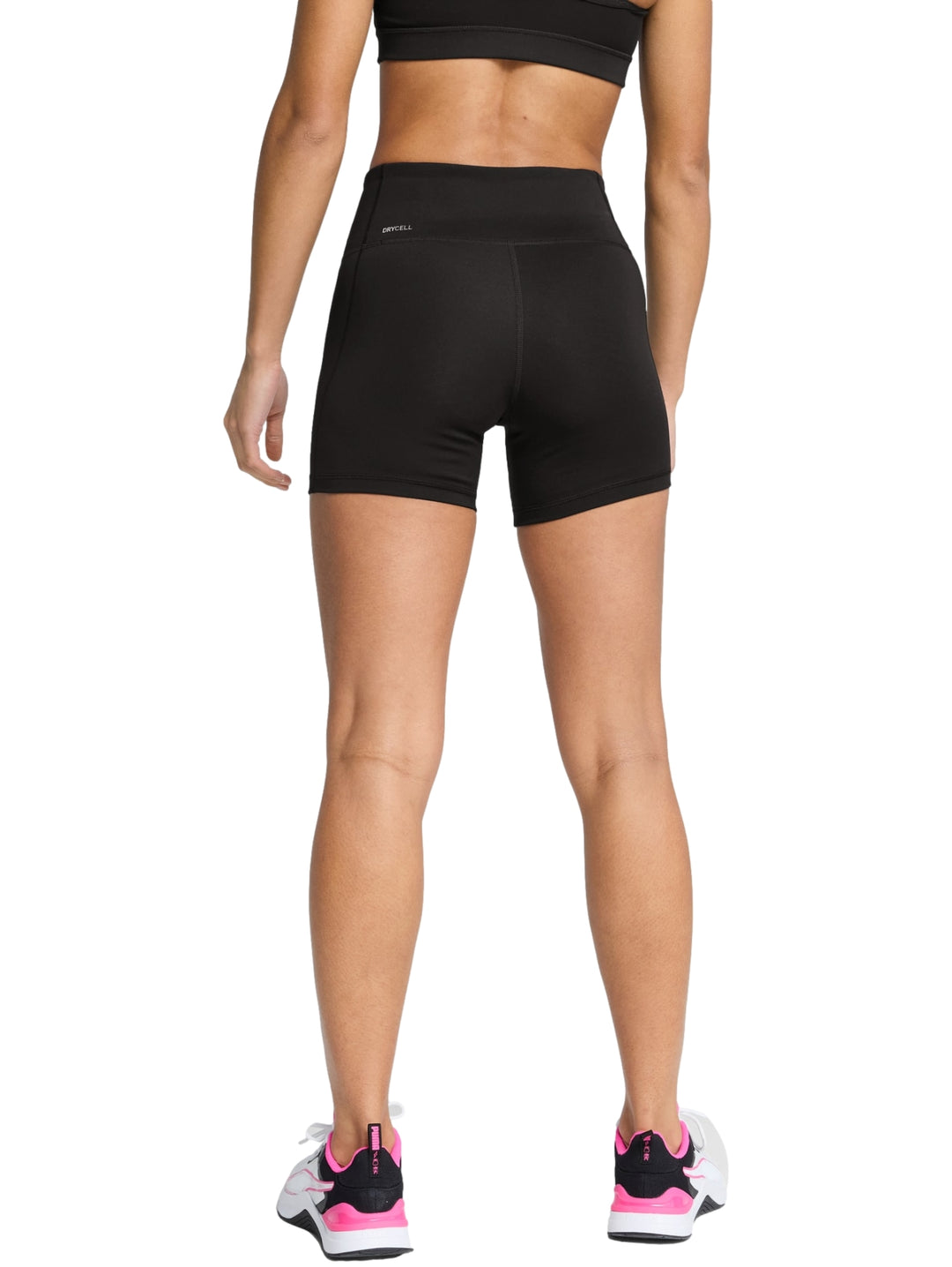 Mujer vistiendo shorts deportivos ajustados de cintura alta color negro marca PUMA.