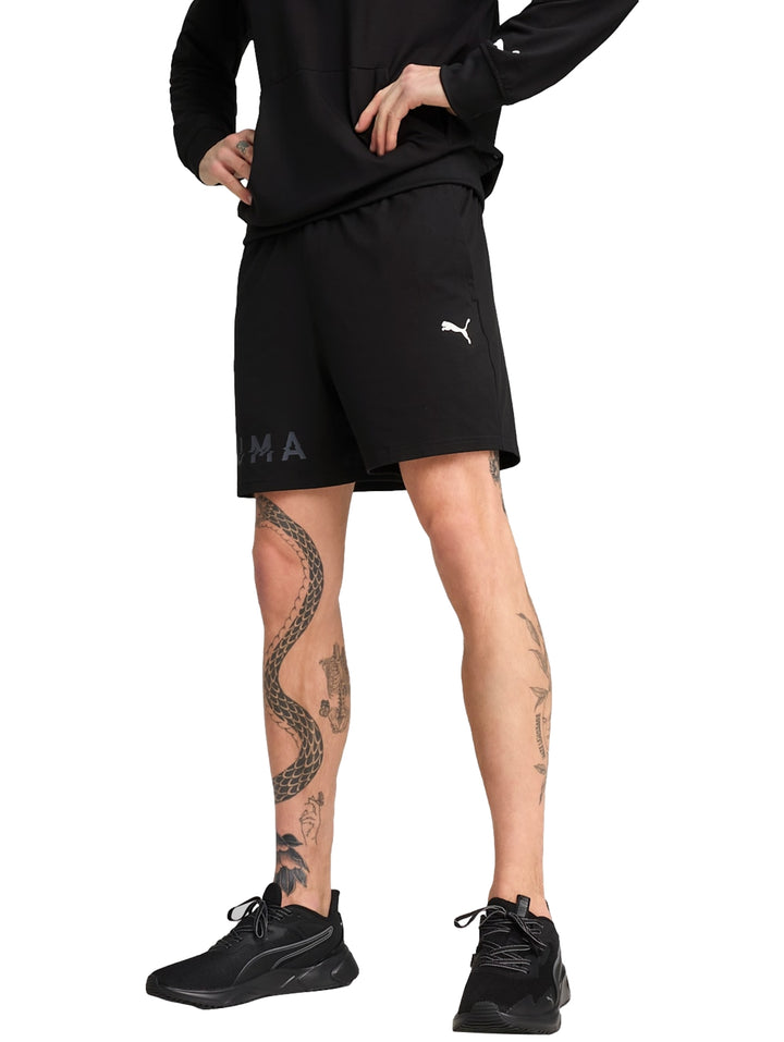 Hombre vistiendo shorts deportivos Puma color negro con logotipo blanco lateral.