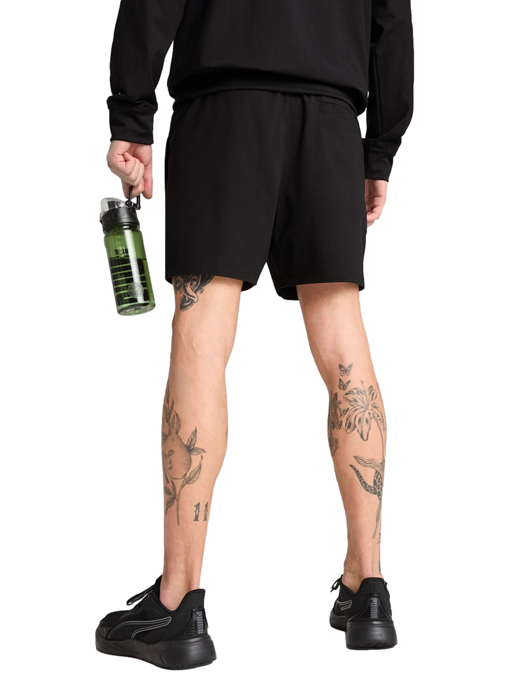 Hombre vistiendo shorts deportivos Puma color negro con logotipo blanco lateral.
