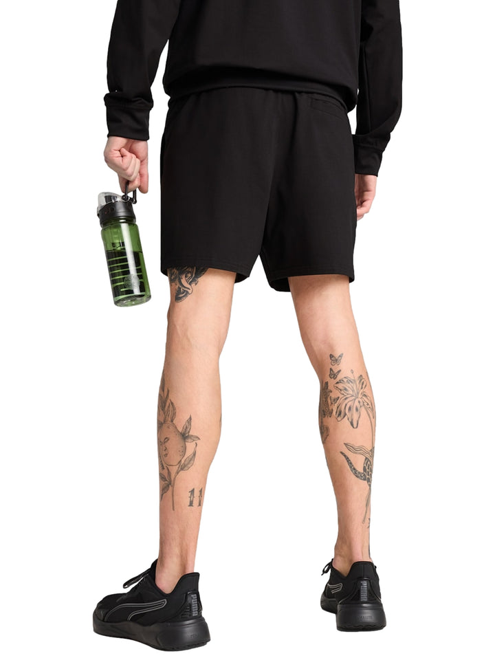 Hombre vistiendo shorts deportivos Puma color negro con logotipo blanco lateral.