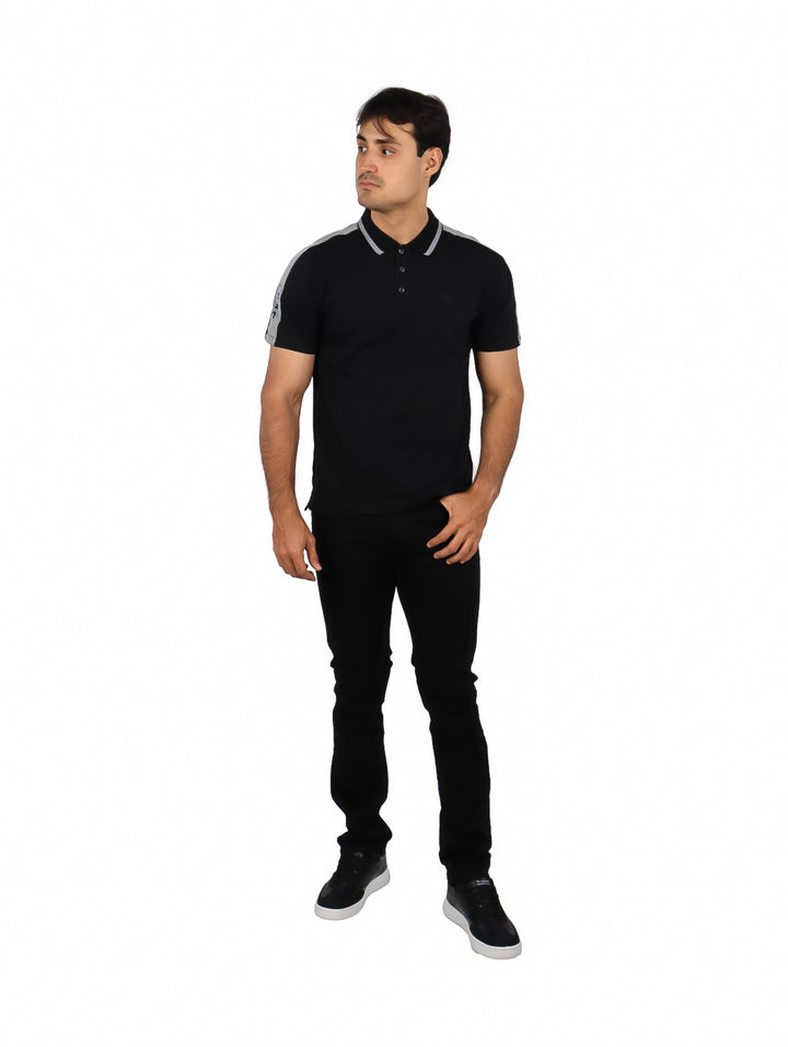 Hombre vistiendo una playera polo color negro con detalles en gris en los hombros y cuello.
