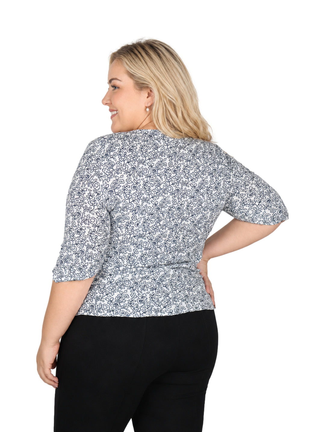Mujer vistiendo blusa blanca con estampado floral marino de manga corta y pantalones negros.