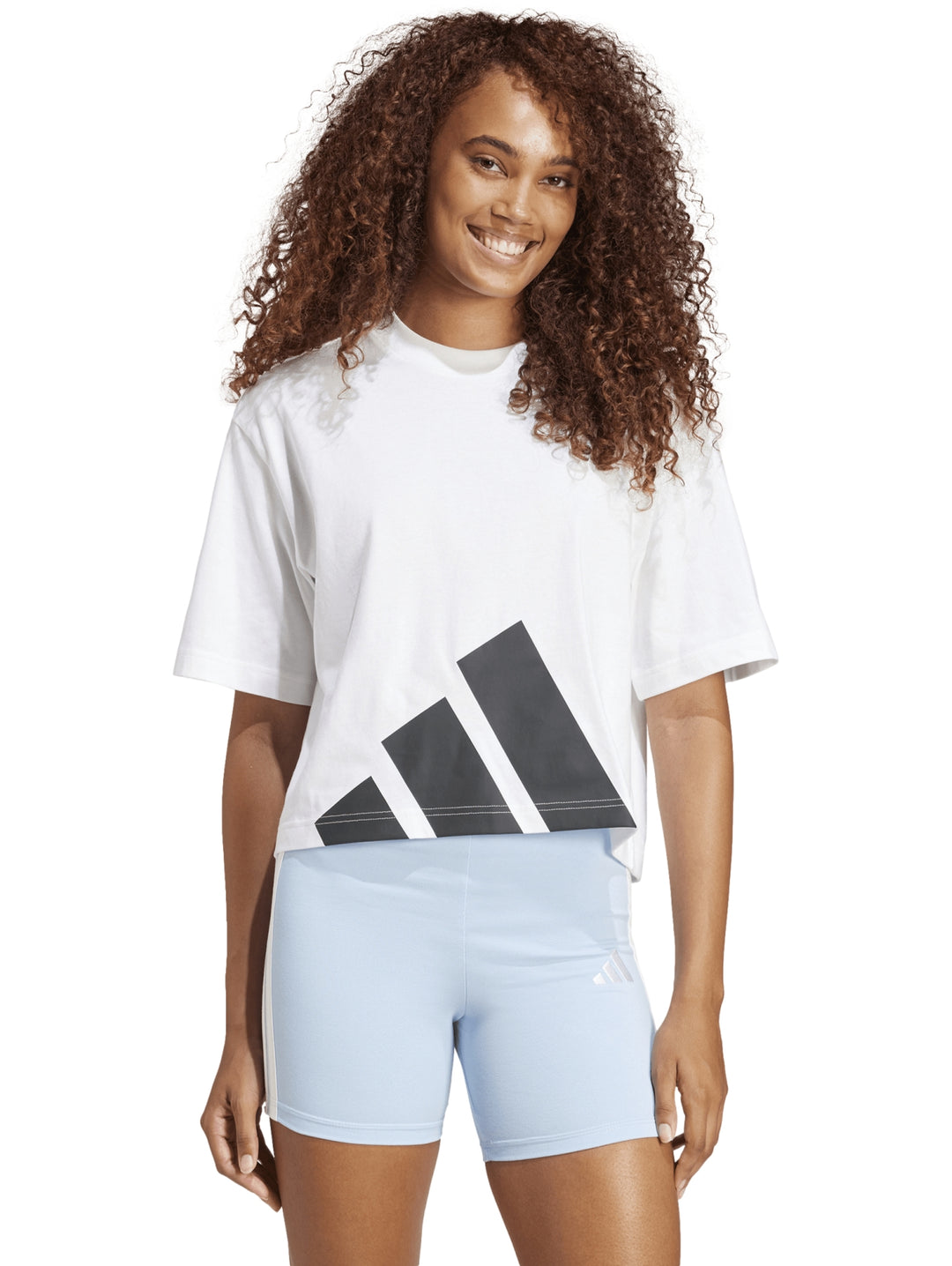 Mujer vistiendo playera blanca Adidas de corte boyfriend con logo grande en negro.