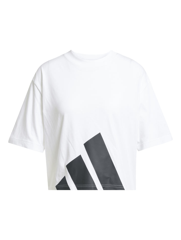 Mujer vistiendo playera blanca Adidas de corte boyfriend con logo grande en negro.