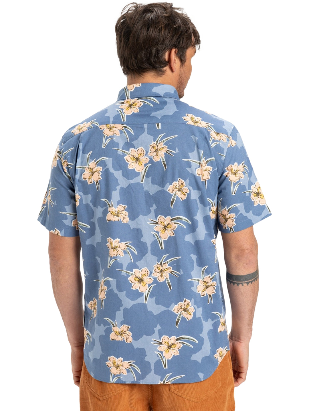Hombre vistiendo camisa de manga corta azul con estampado floral en tonos crema.