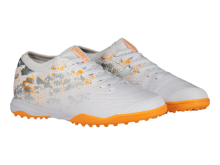 Zapato de fútbol Charly color blanco con suela naranja y detalles decorativos en gris.