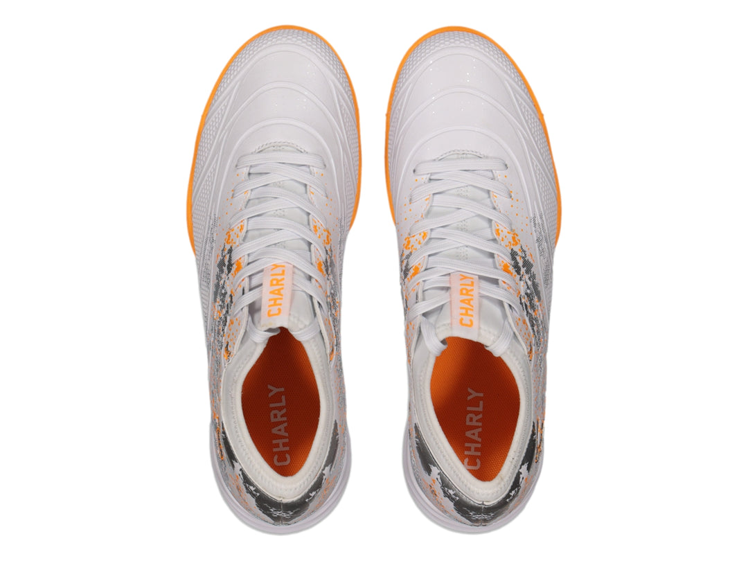 Zapato de fútbol Charly color blanco con suela naranja y detalles decorativos en gris.