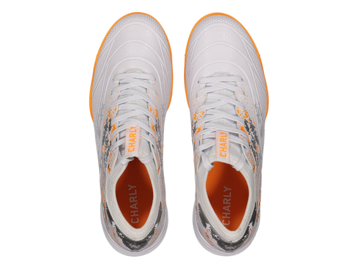 Zapato de fútbol Charly color blanco con suela naranja y detalles decorativos en gris.