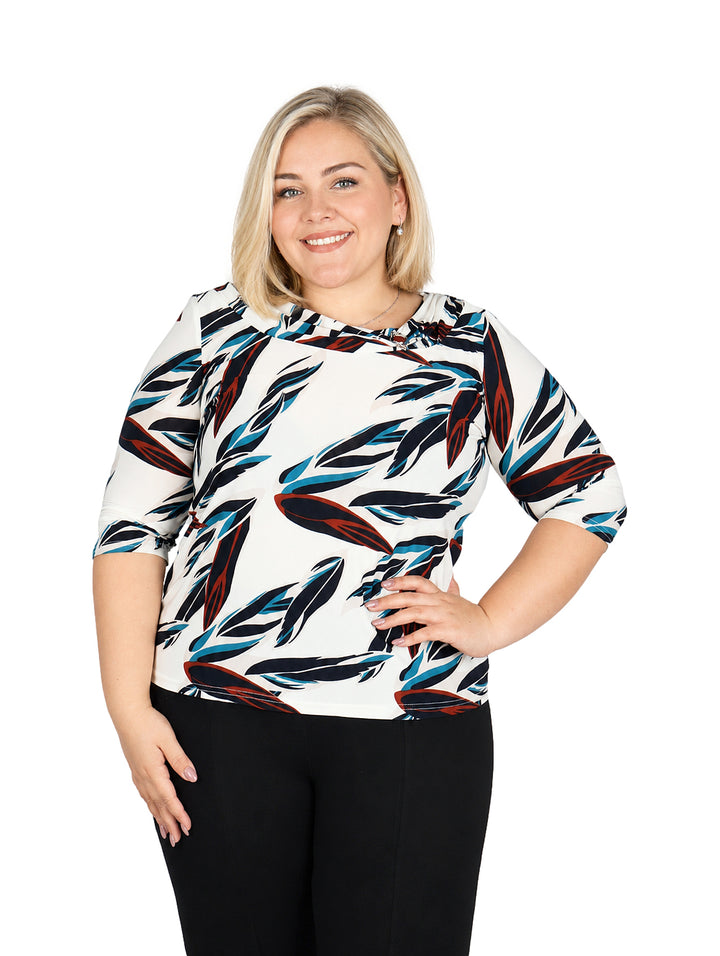 Mujer vistiendo blusa blanca con estampado de hojas en azul y rojo, de manga corta.