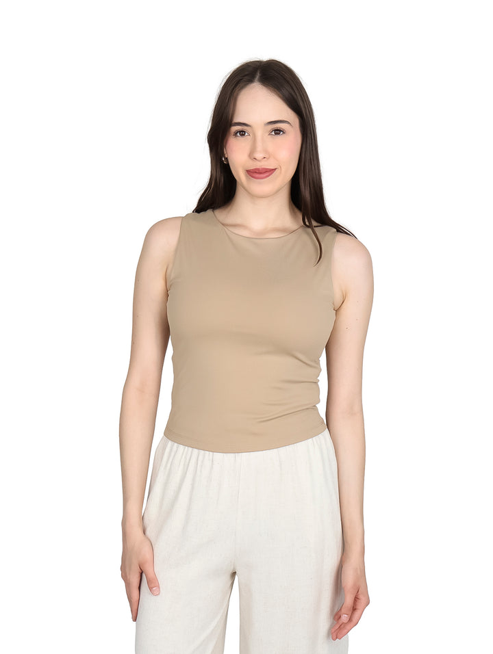 Mujer modelando una blusa sin mangas de color kaki y pantalones blancos.