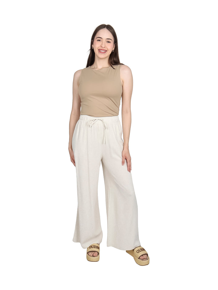 Mujer modelando una blusa sin mangas de color kaki y pantalones blancos.