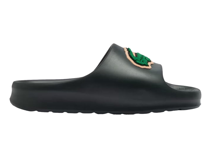 Sandalia tipo slide de color verde oscuro con el logotipo del cocodrilo verde de Lacoste en la banda superior.
