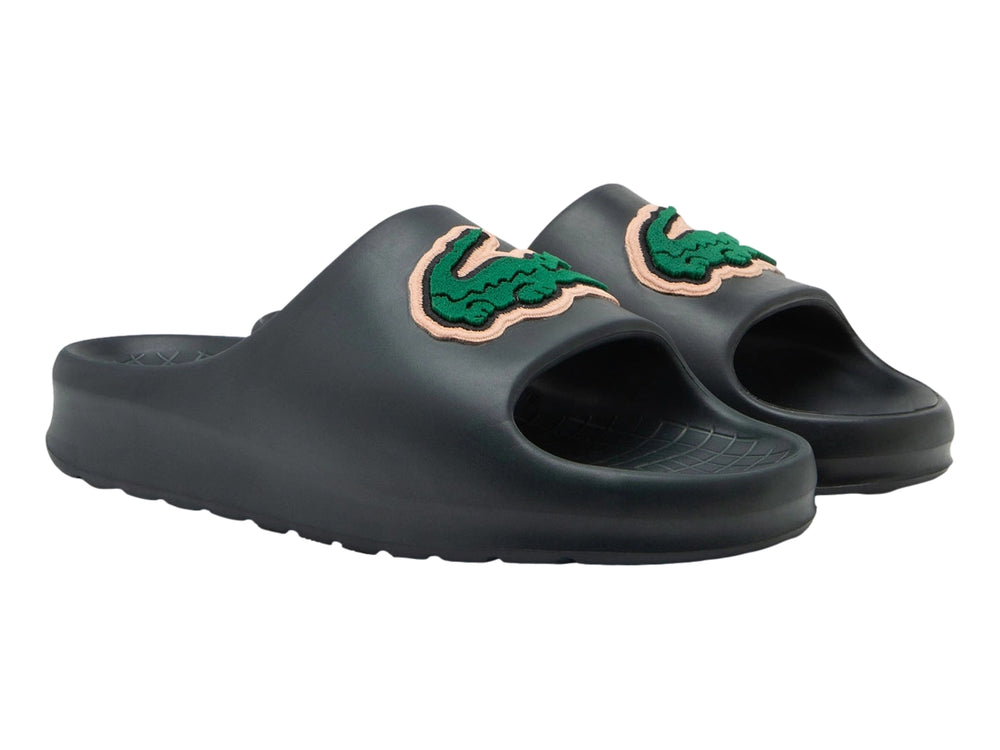 Sandalia tipo slide de color verde oscuro con el logotipo del cocodrilo verde de Lacoste en la banda superior.