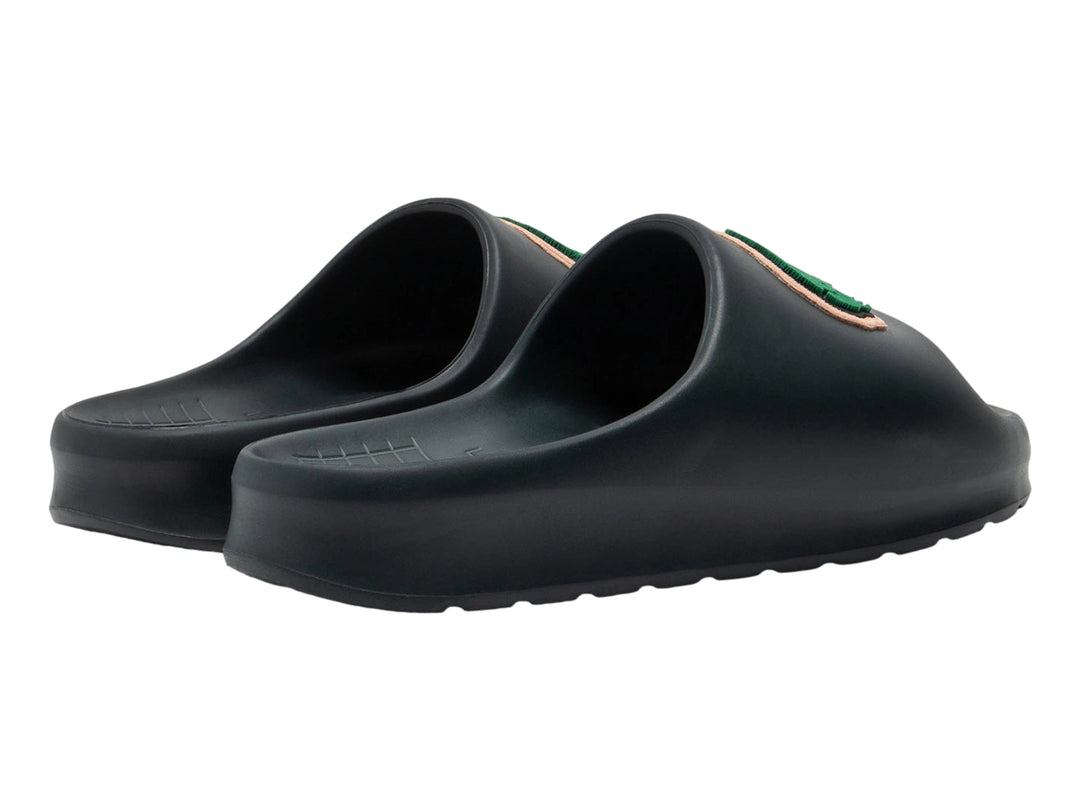 Sandalia tipo slide de color verde oscuro con el logotipo del cocodrilo verde de Lacoste en la banda superior.
