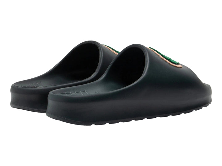 Sandalia tipo slide de color verde oscuro con el logotipo del cocodrilo verde de Lacoste en la banda superior.