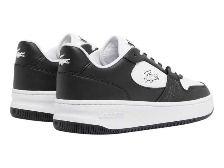 Tenis deportivos Lacoste para niño en colores blanco y negro con logotipo del cocodrilo lateral.