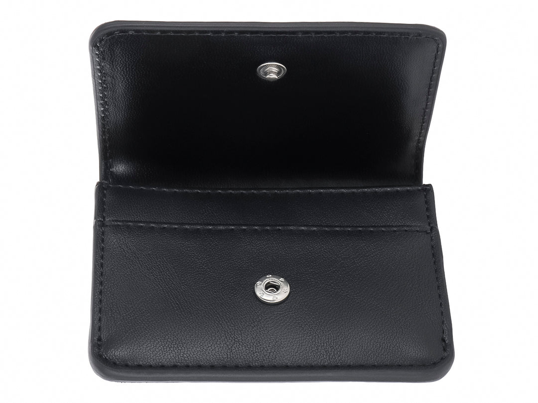 Cartera pequeña de color negro con textura rugosa y logotipo SM en metal plateado al frente.