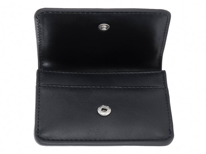 Cartera pequeña de color negro con textura rugosa y logotipo SM en metal plateado al frente.