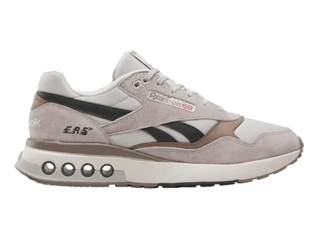 Tenis Reebok modelo ERS World en color gris con detalles en negro y suela blanca con amortiguadores visibles.