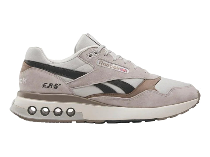 Tenis Reebok modelo ERS World en color gris con detalles en negro y suela blanca con amortiguadores visibles.