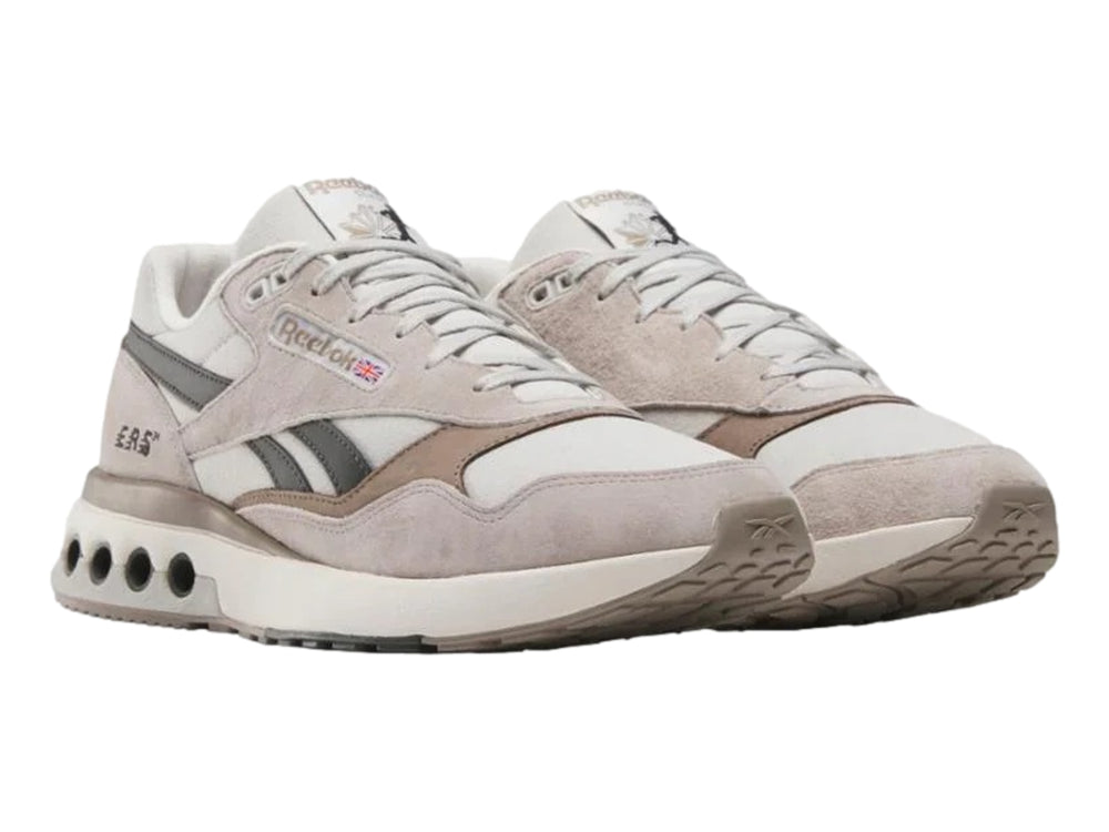 Tenis Reebok modelo ERS World en color gris con detalles en negro y suela blanca con amortiguadores visibles.