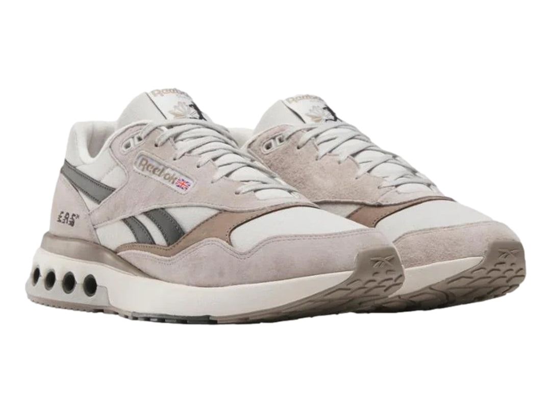 Tenis Reebok modelo ERS World en color gris con detalles en negro y suela blanca con amortiguadores visibles.