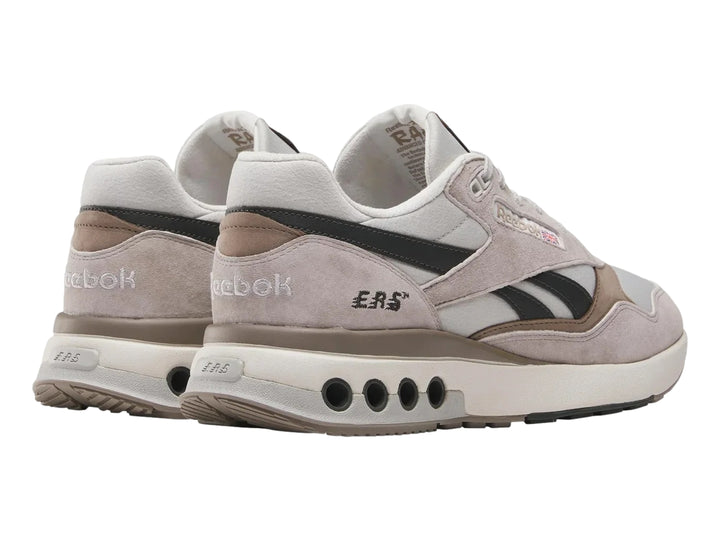 Tenis Reebok modelo ERS World en color gris con detalles en negro y suela blanca con amortiguadores visibles.
